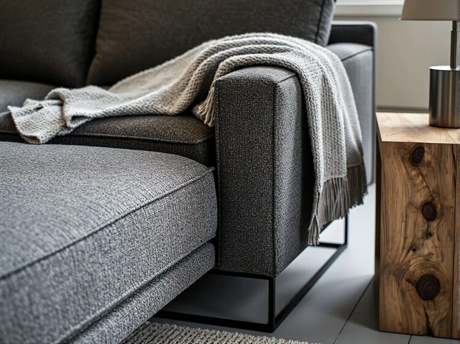 Szary tapicerowany narożnik na metalowych nóżkach idealny do nowoczesnego wnętrza typu loft